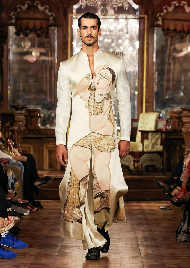 A male model walks in an ivory couture sherwani featuring a large Kalighat-inspired painted figure
